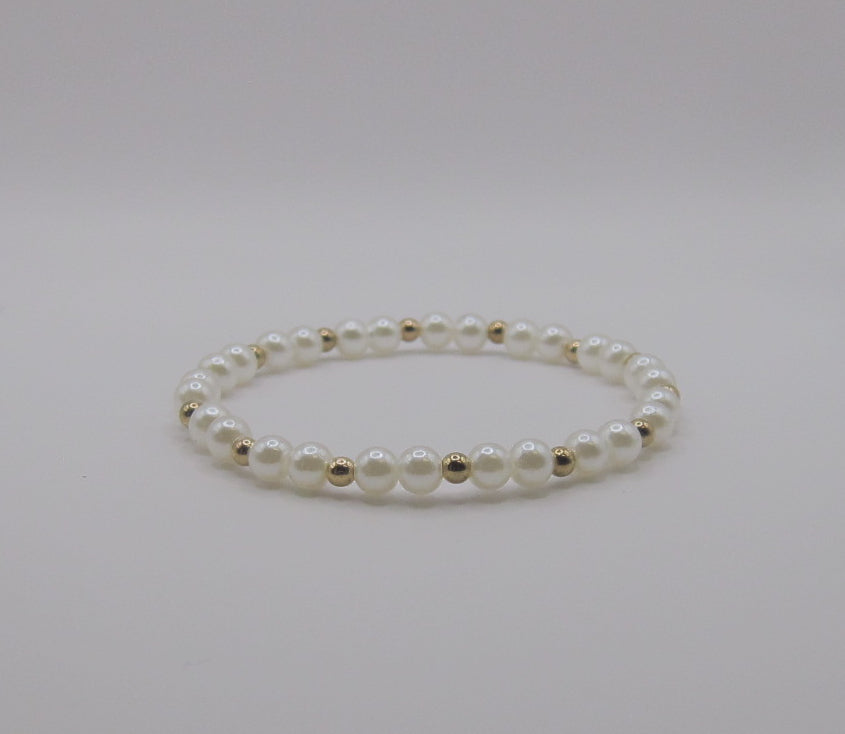 Pearl bracelet with gold accents on a light gray background